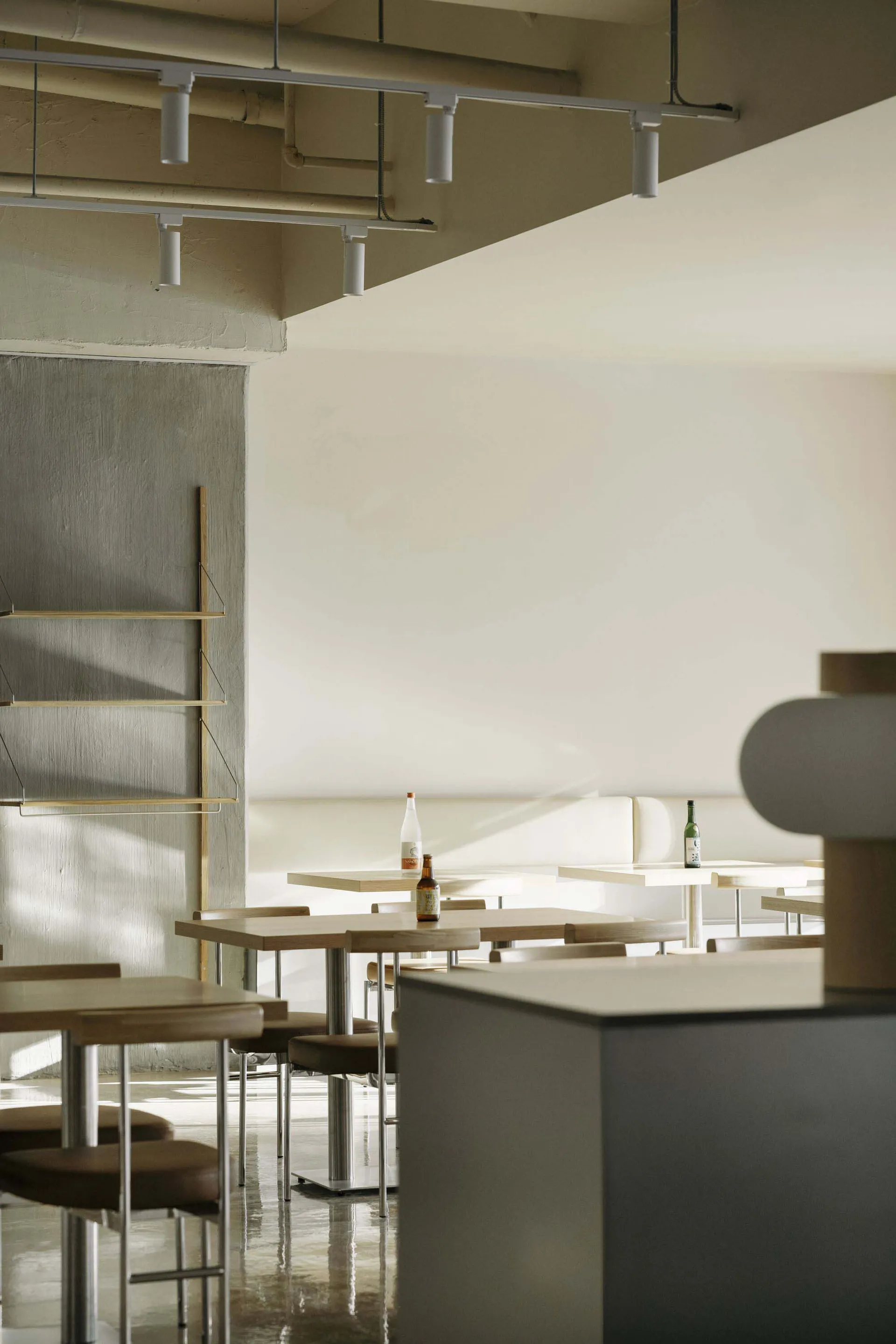 A modern restaurant interior featuring minimalist design, wooden tables, and concrete finishes.