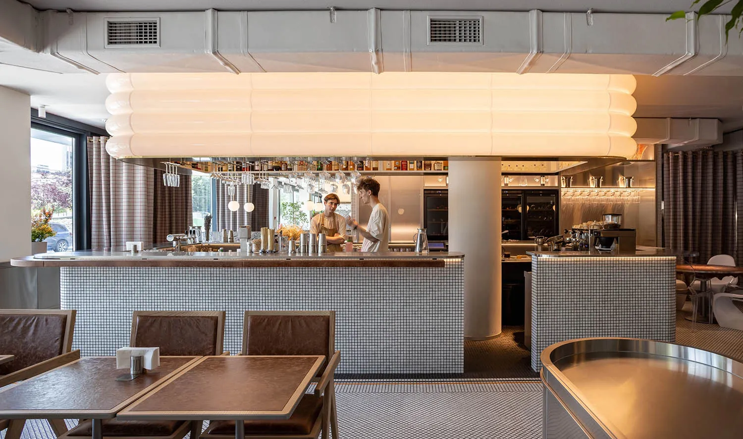A photograph of a modern restaurant interior featuring tile and metal finishes.