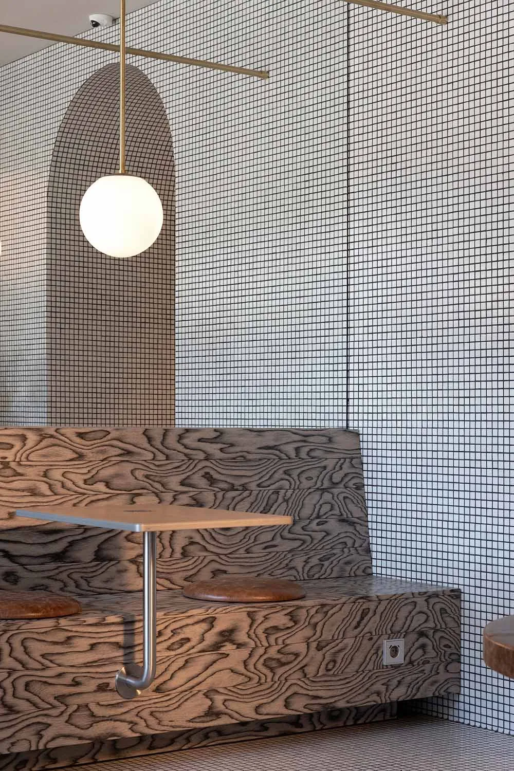 A modern restaurant setting featuring a wooden booth with a grid-patterned wall, designed to evoke an industrial aesthetic.
