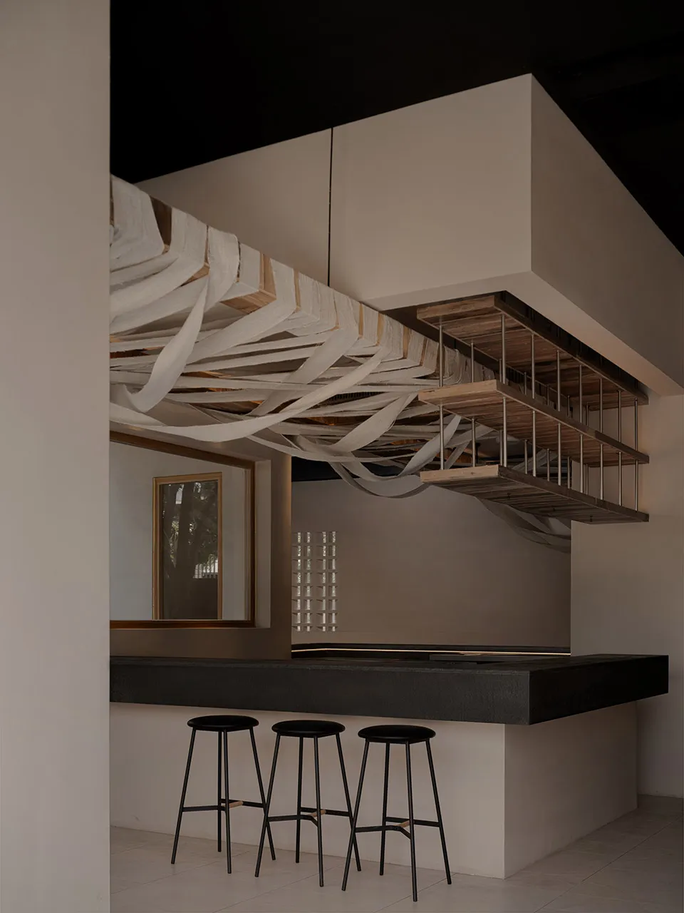 Modern interior design featuring a concrete bar counter with three stools.