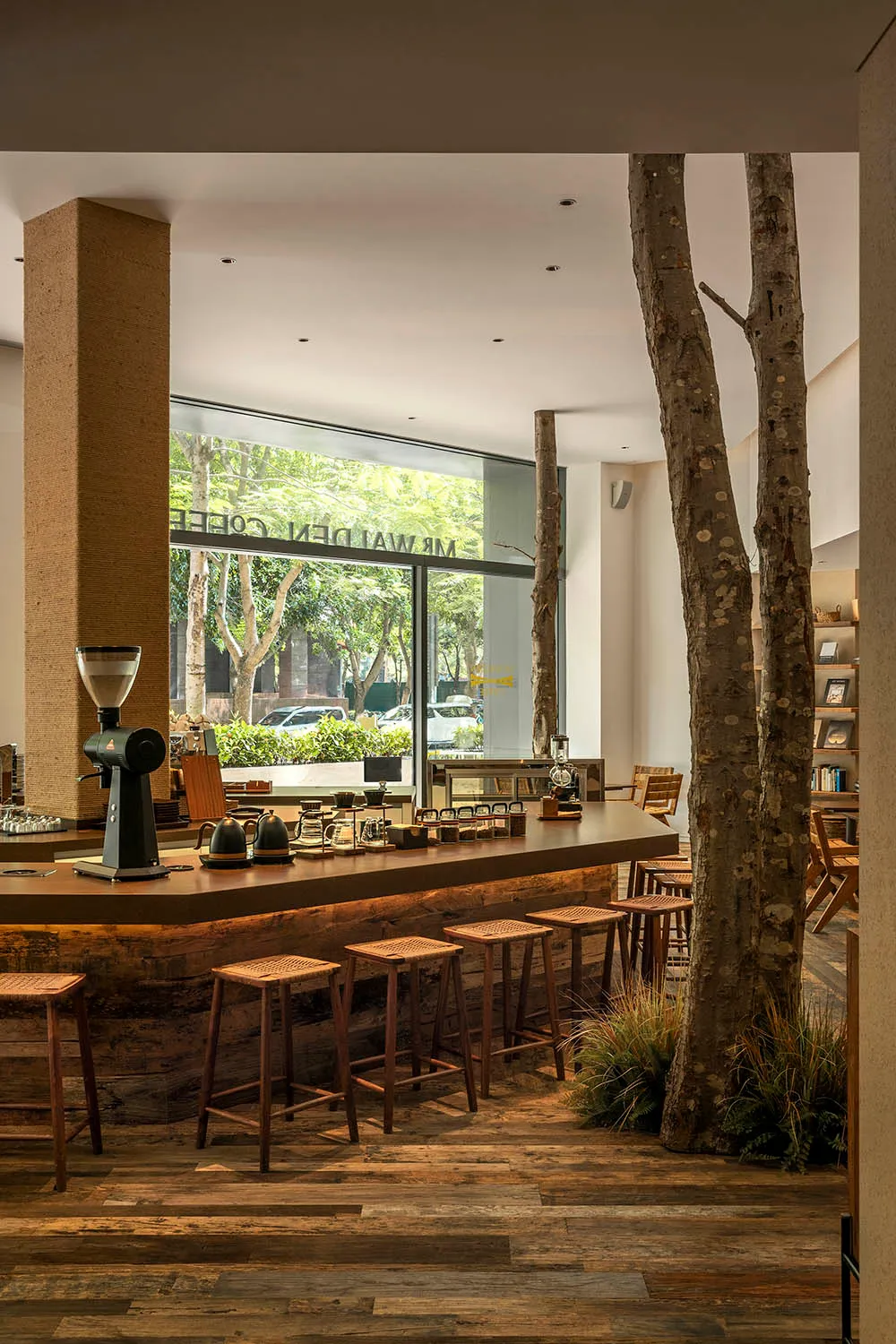 Interior design of a modern coffee shop bar with a rustic wooden counter and stools, featuring a minimalist aesthetic and nat