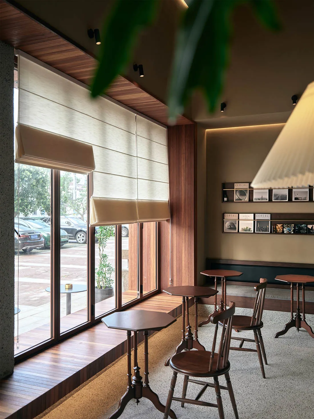 Cafe interior with wooden tables, chairs, and a window with blinds.