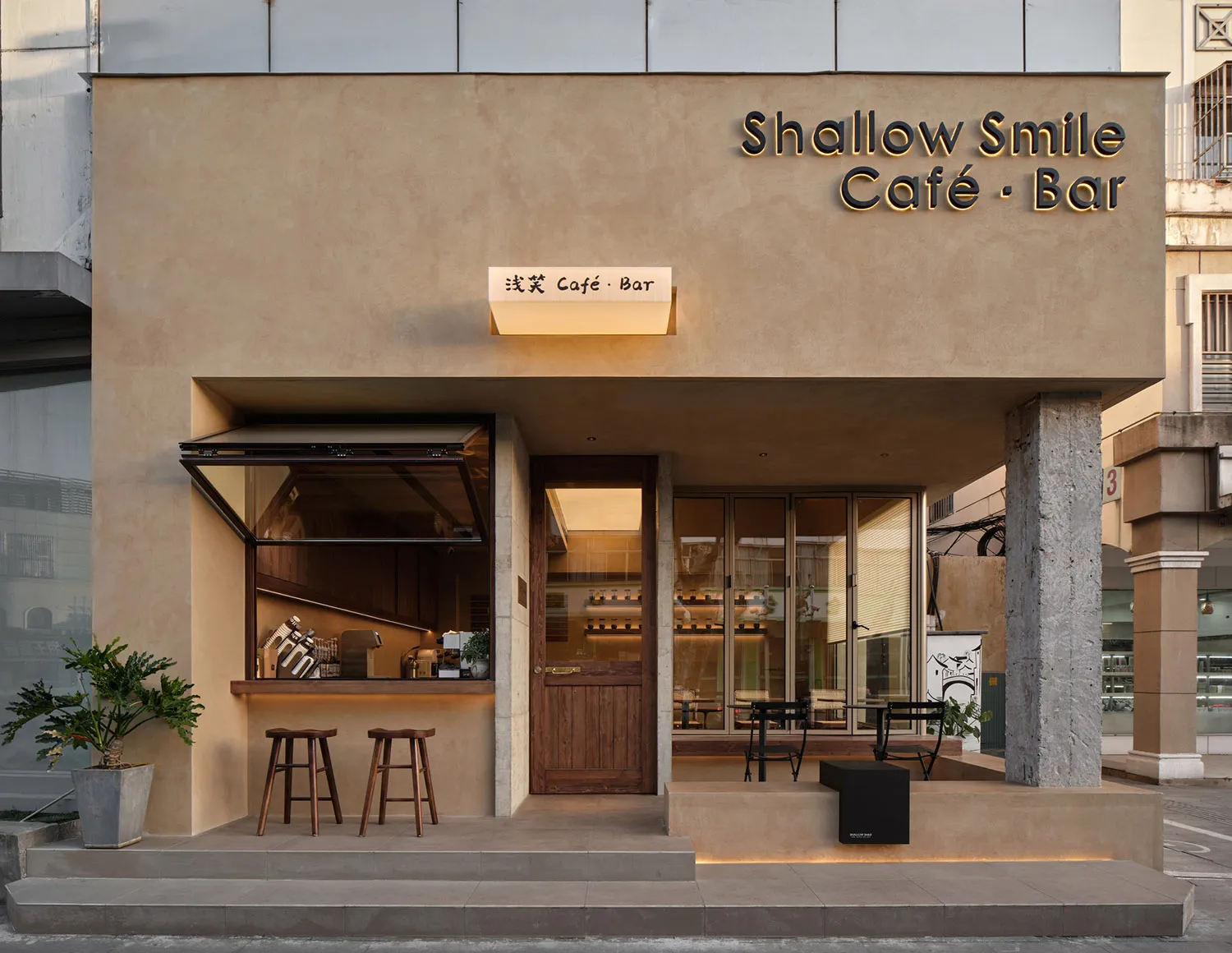 Shallow Smile Cafe Bar 店面採用混凝土外牆，搭配木質細節與玻璃窗。