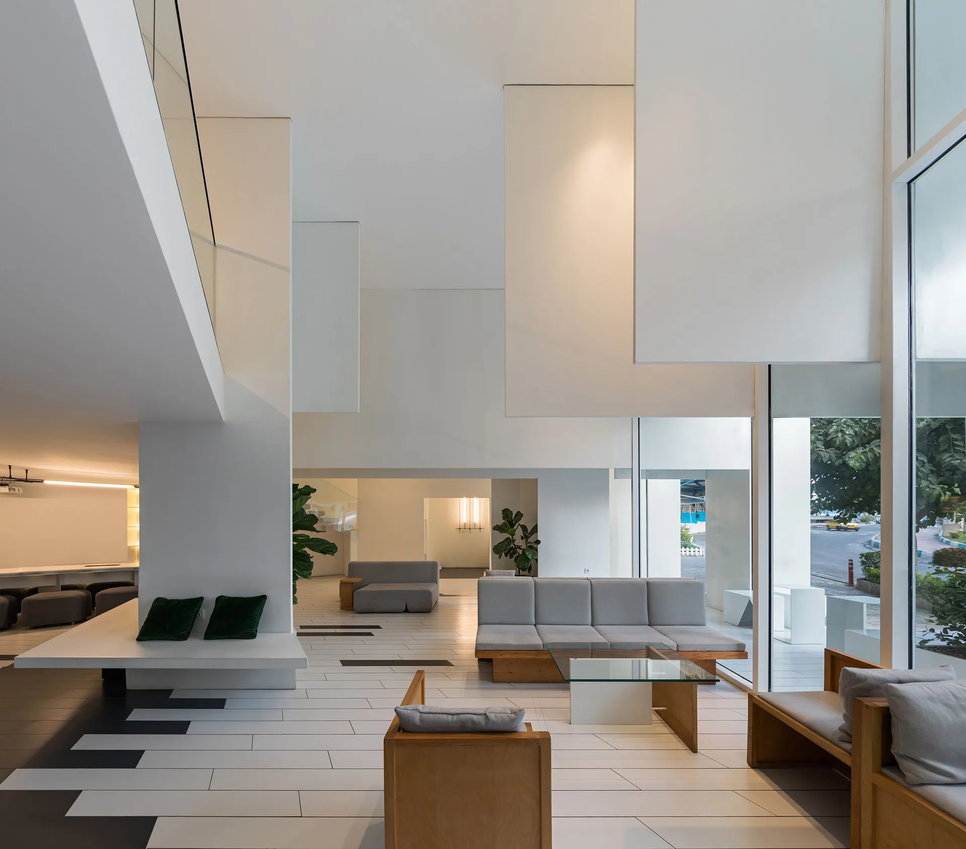 A modern living room featuring minimalist furniture, concrete walls, wooden accents, and large windows with a view of the str