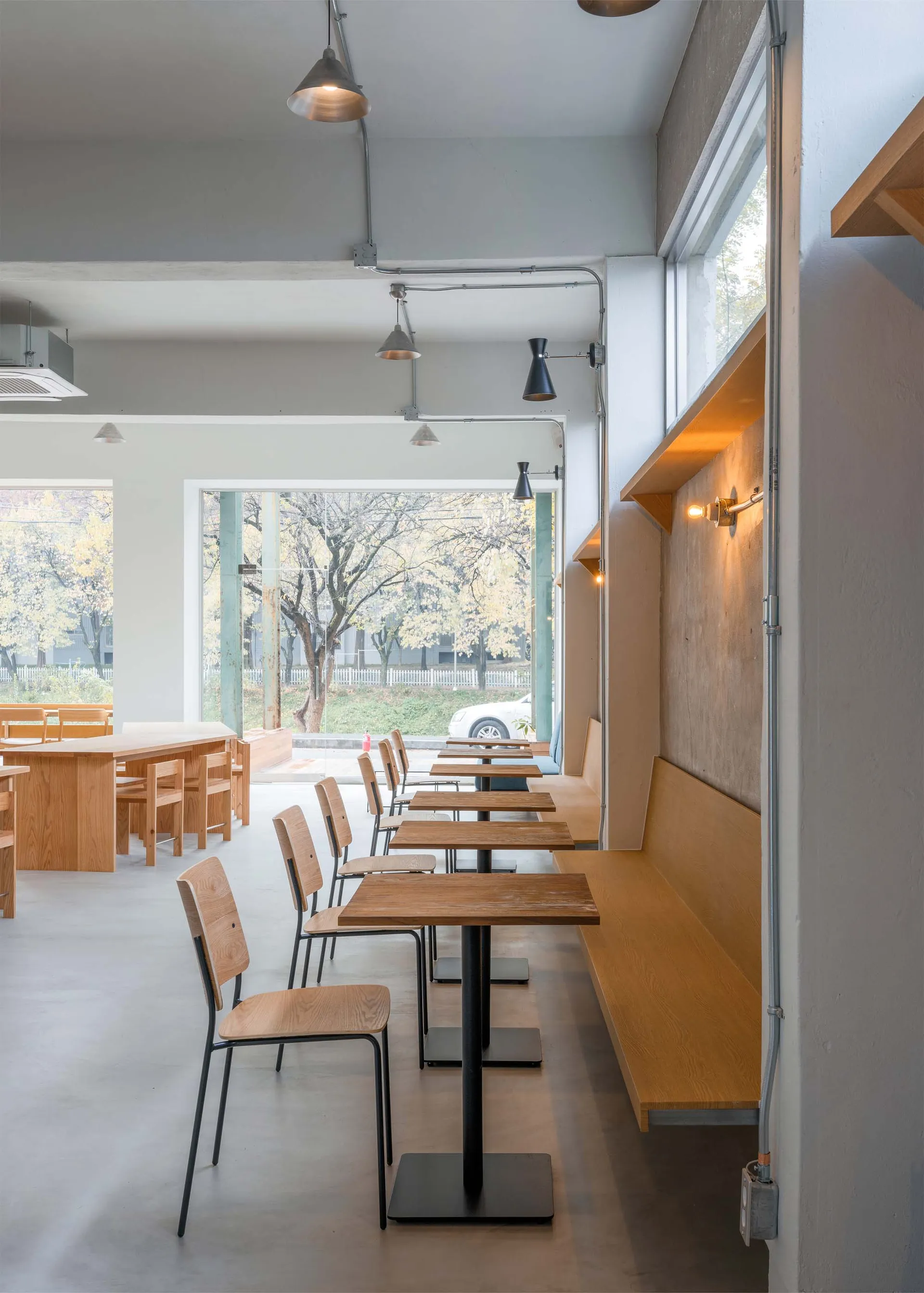 A minimalist cafe interior with wooden tables, chairs, and benches.