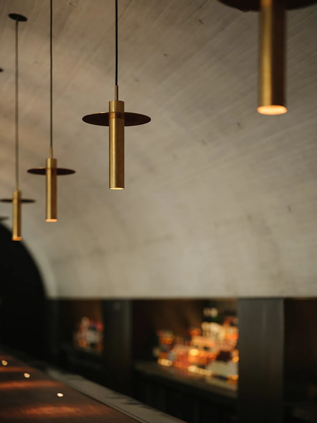 Industrial-style interior design featuring brass pendant lights over a bar counter.