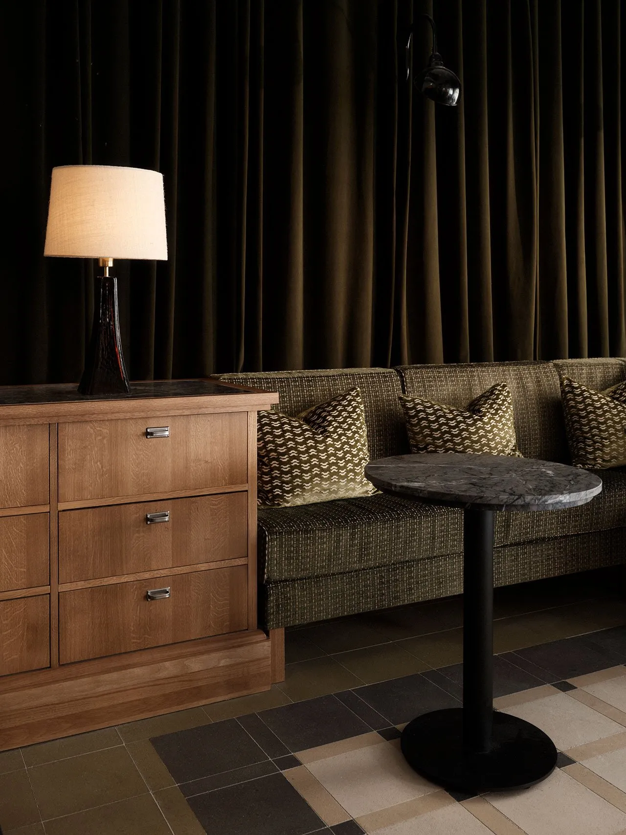 Modern living room with wood cabinet, marble table, green sofa, and fabric pillows.