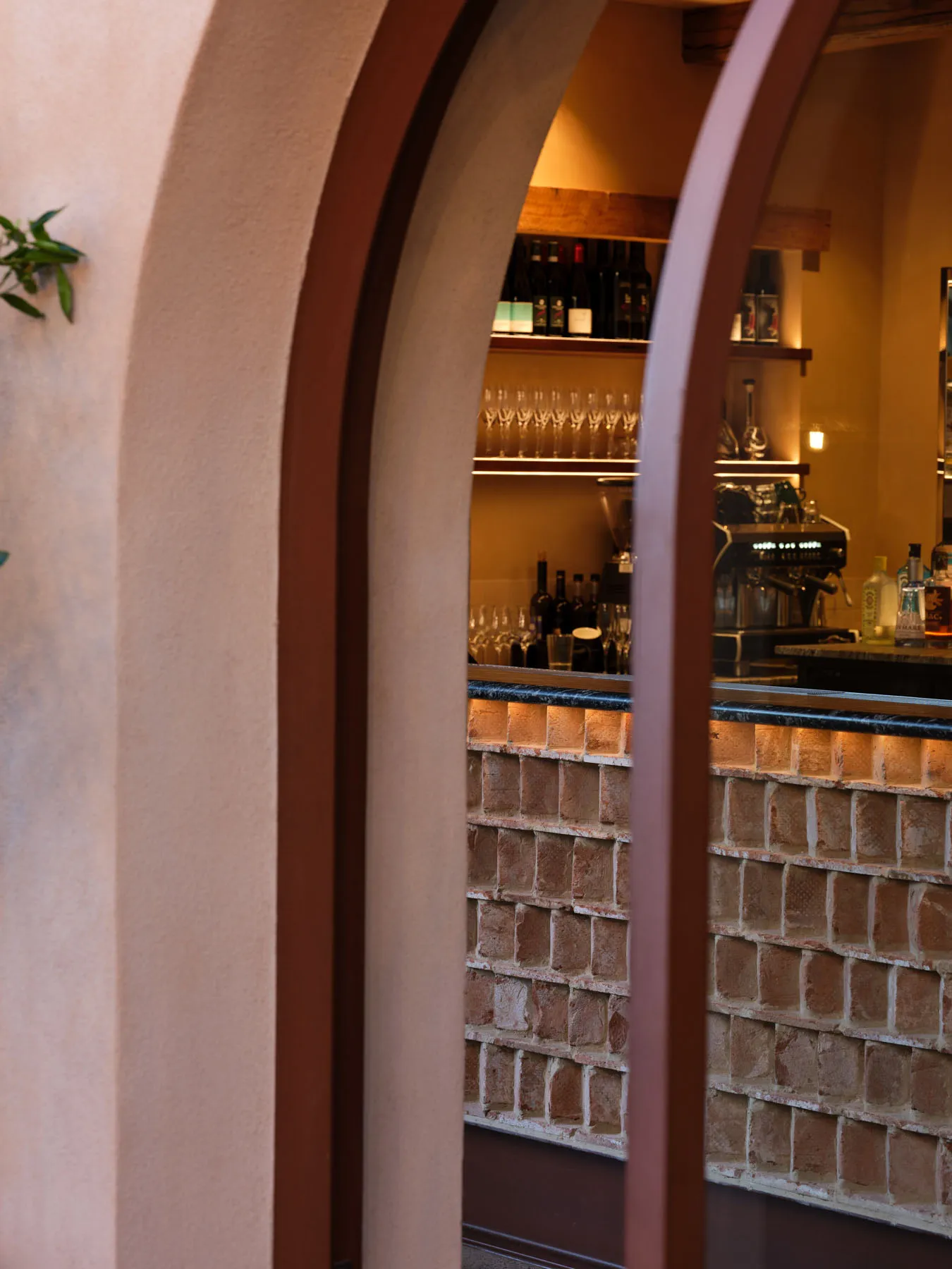 A modern restaurant bar with brick walls and concrete counter, showcasing sleek design elements and contemporary aesthetic.