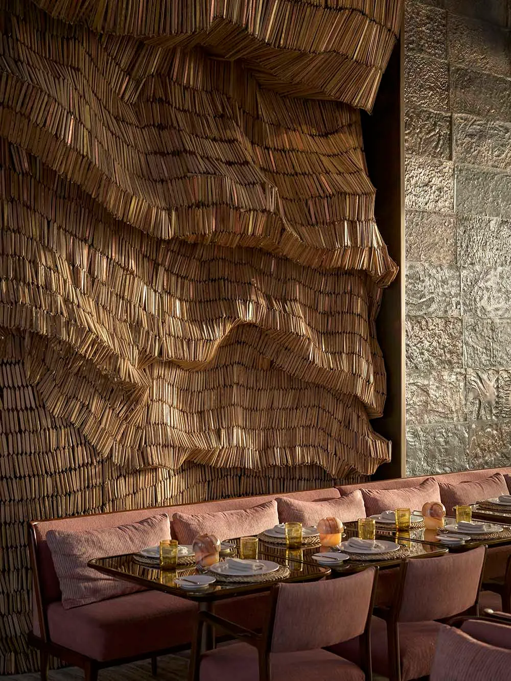 Modern restaurant interior with a textured, wavy wood wall and comfortable seating arrangement.