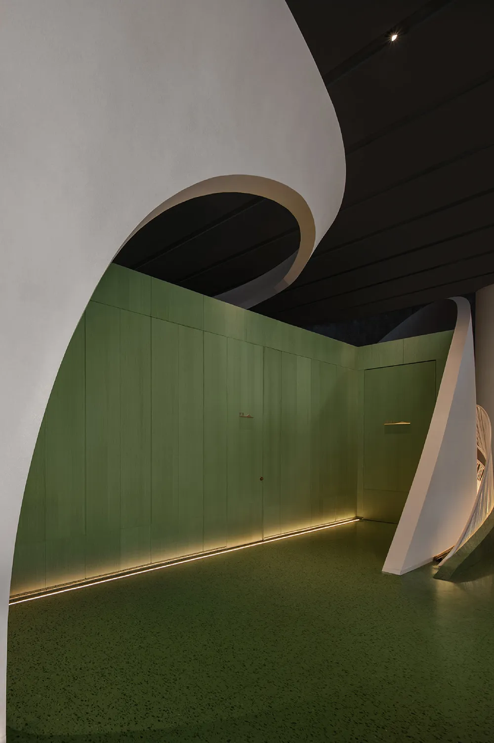 A modern interior space with green walls and concrete surfaces.