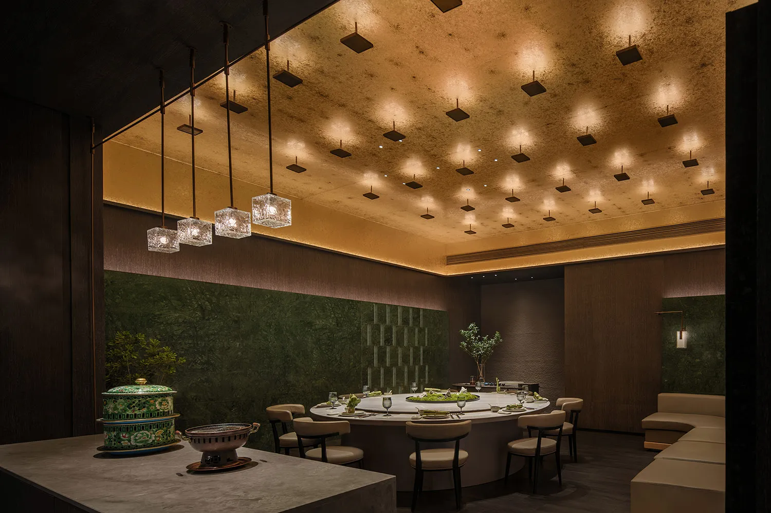 A modern restaurant with marble and concrete walls, featuring a large dining table and pendant lights.