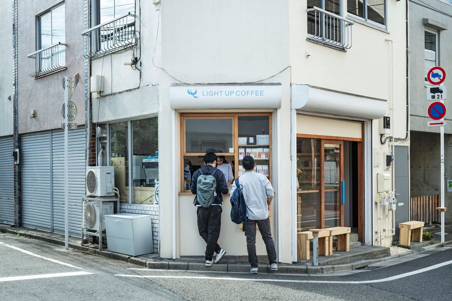 一間現代街角咖啡店，擁有白色牆面與玻璃落地窗。