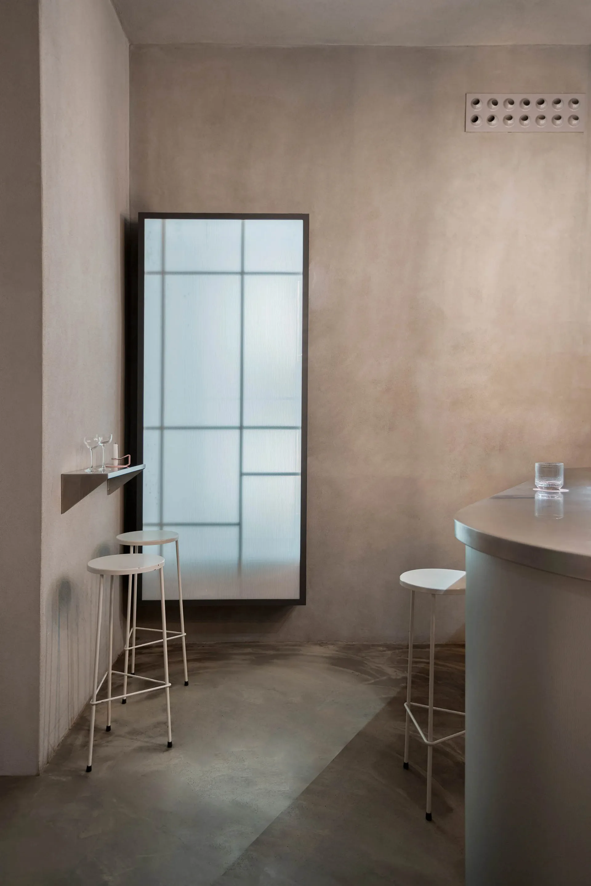 A minimalist bar area with concrete and glass materials.