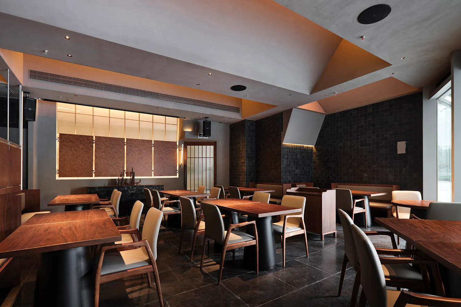 A modern restaurant interior featuring wooden tables and chairs, with a minimalist design aesthetic.