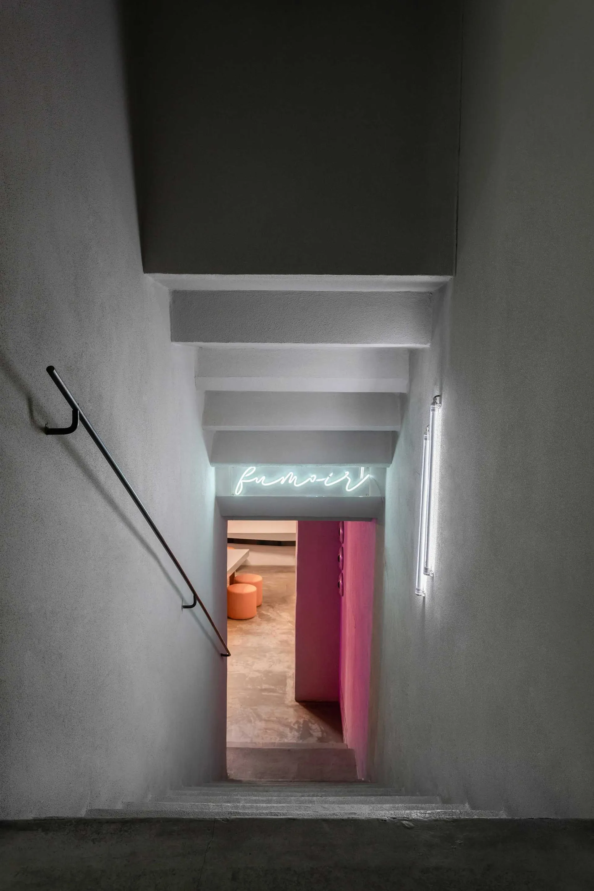Concrete stairwell with neon signage and modern lighting fixtures.