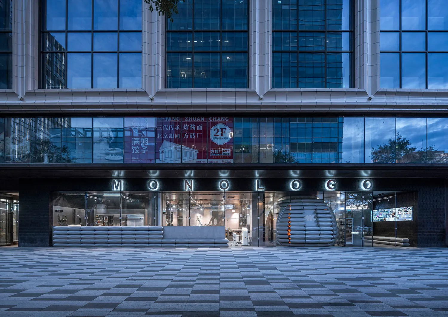 Modern storefront with glass facade, metal railings, and concrete elements.