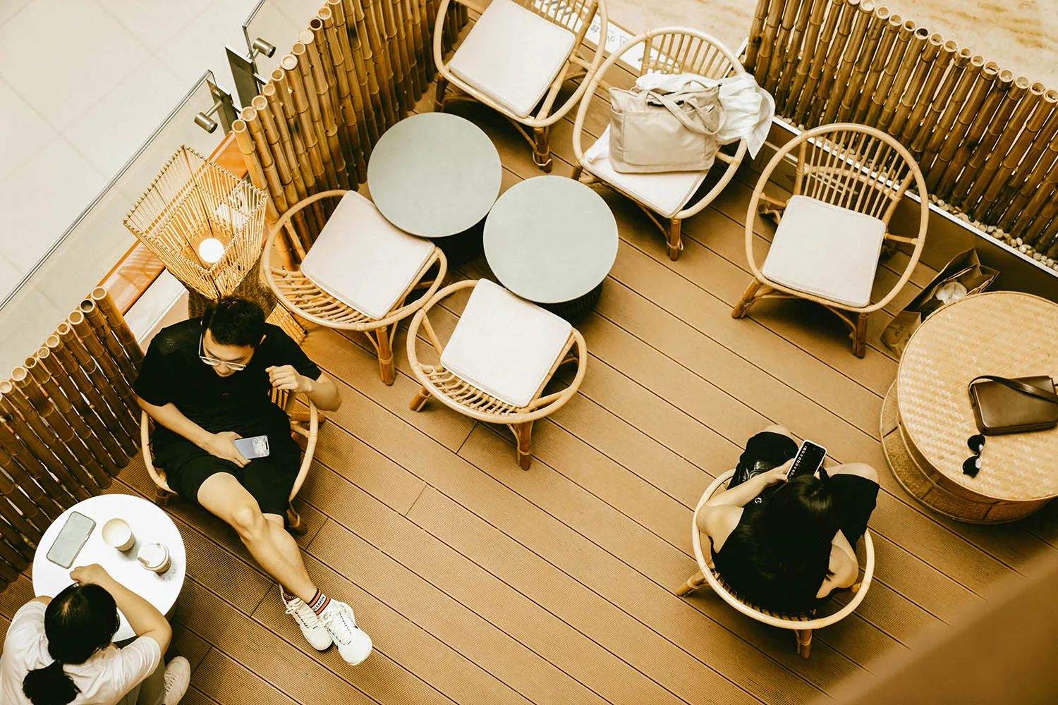 People sitting at bamboo furniture in a cafe with concrete flooring