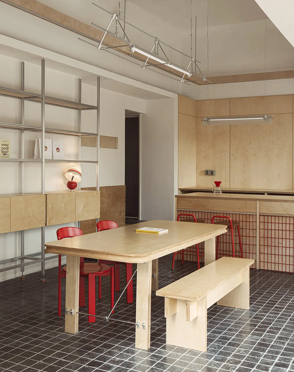 A minimalist commercial kitchen with wooden materials and a red chair.