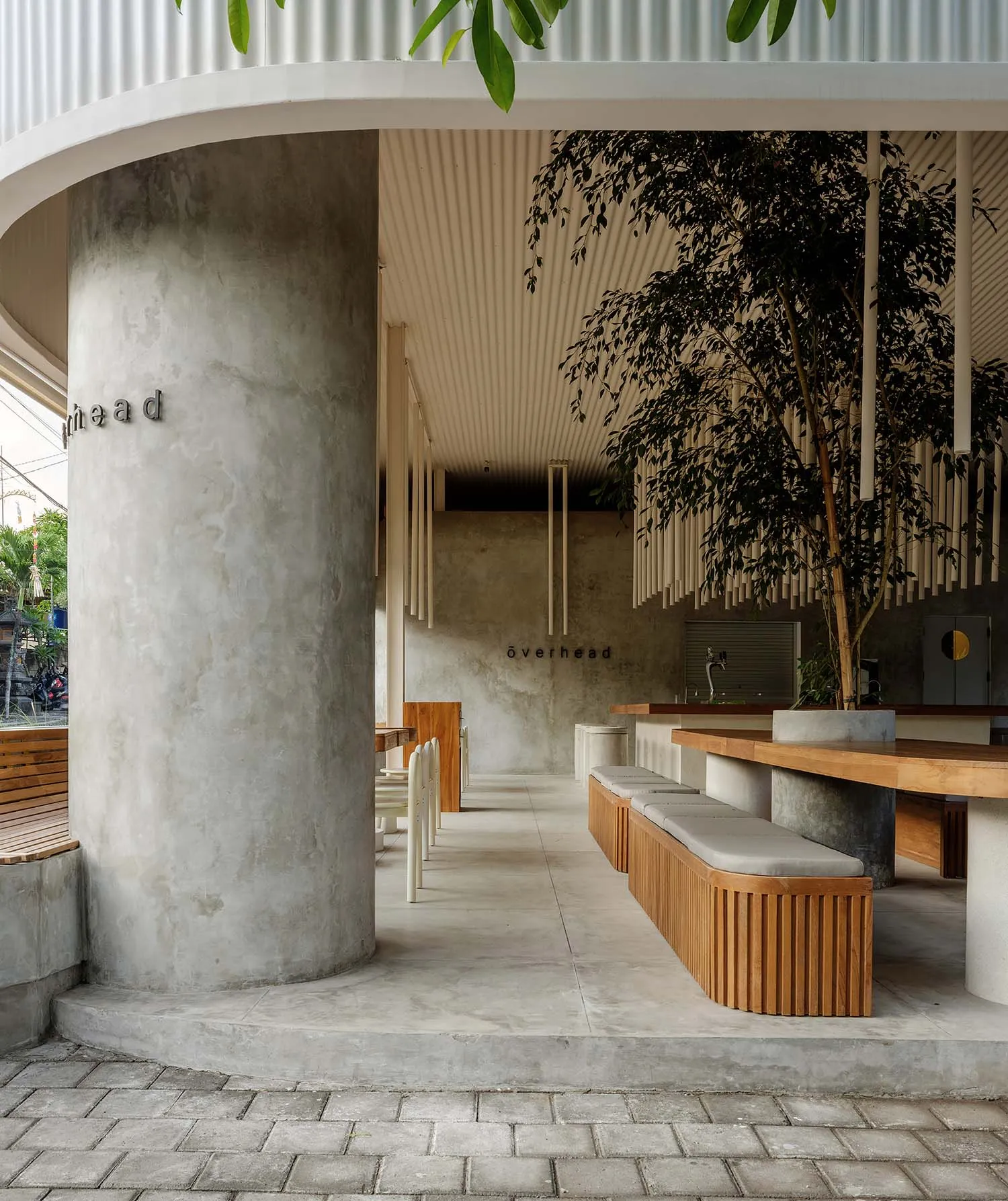 A minimalist food hall with concrete walls, wooden benches, and pendant lighting.