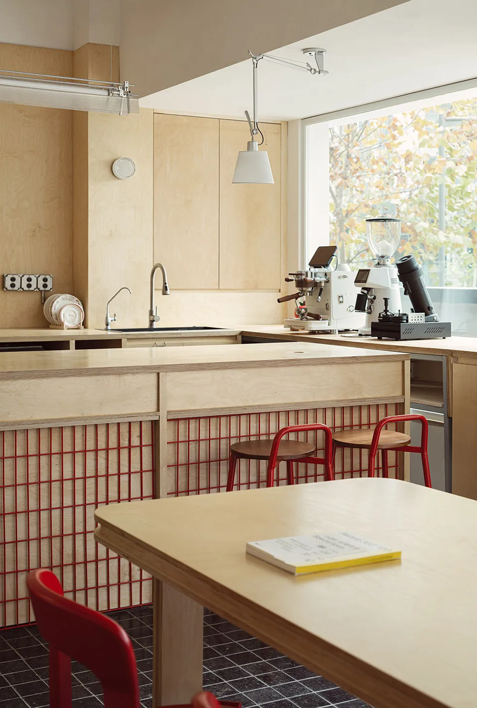 Modern kitchen interior with wooden countertops, metal stools, and minimalist design.