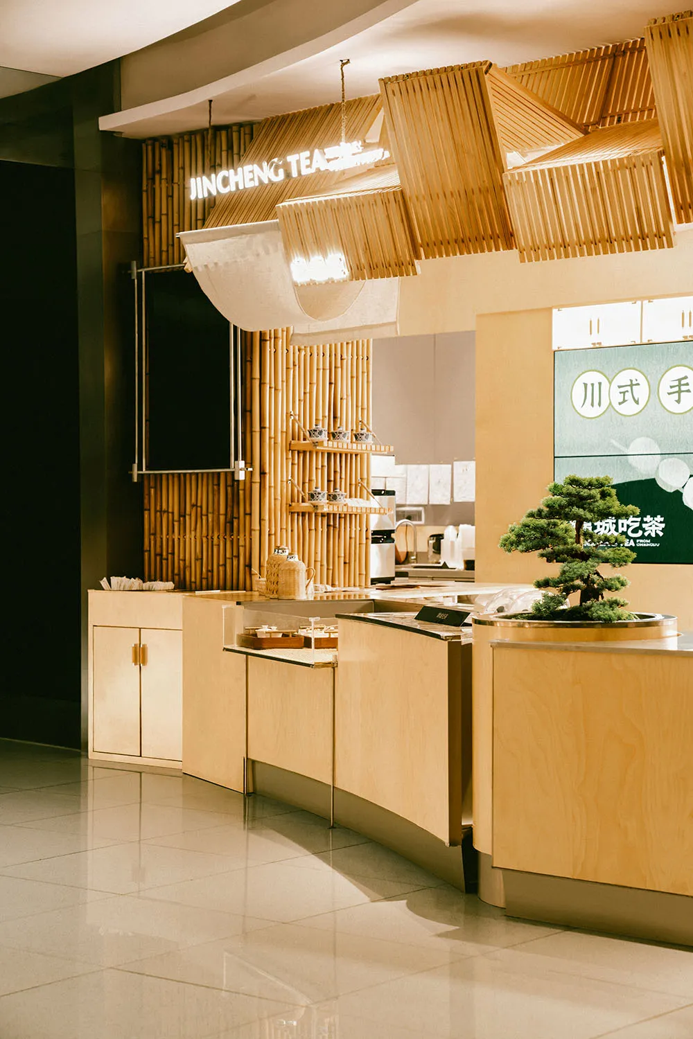 現代餐廳室內空間,採用木質與竹製裝飾,設有吧台並懸掛「金城茶」招牌。