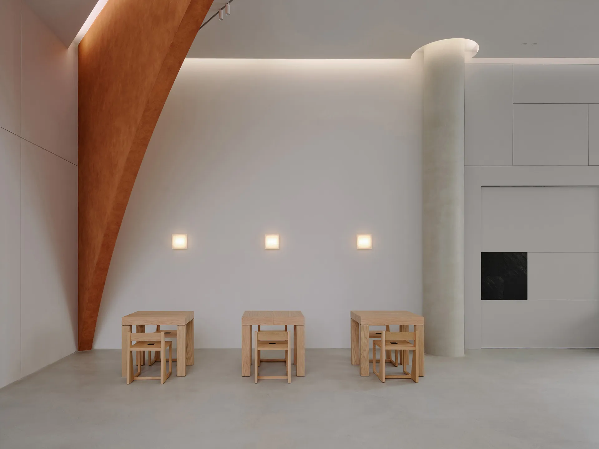 A minimalist room with wooden furniture and concrete flooring.
