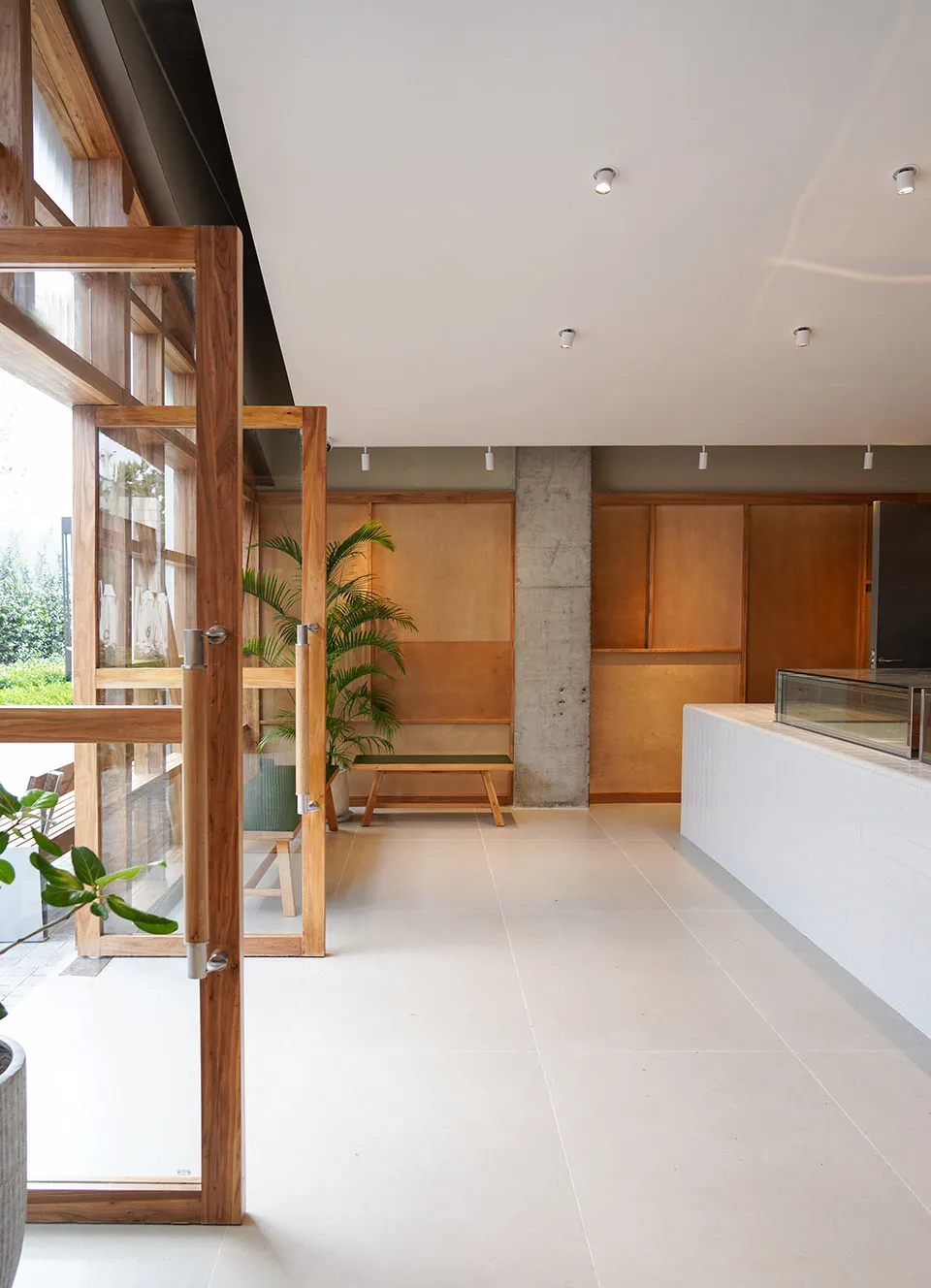 Modern coffee shop with wooden seating, concrete finishes, and large glass windows