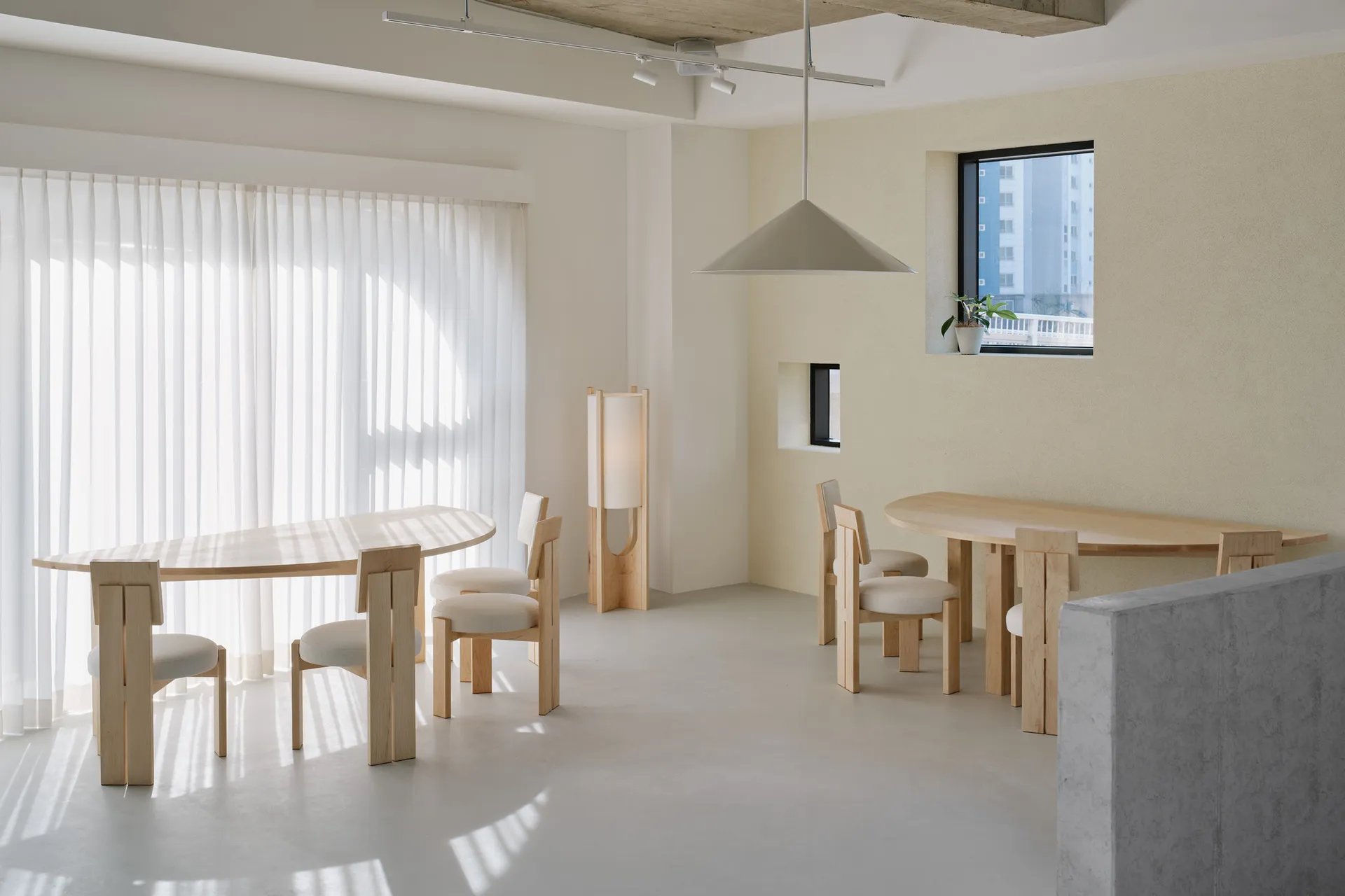 A minimalist co-working space featuring wooden tables, concrete surfaces, and glass elements.