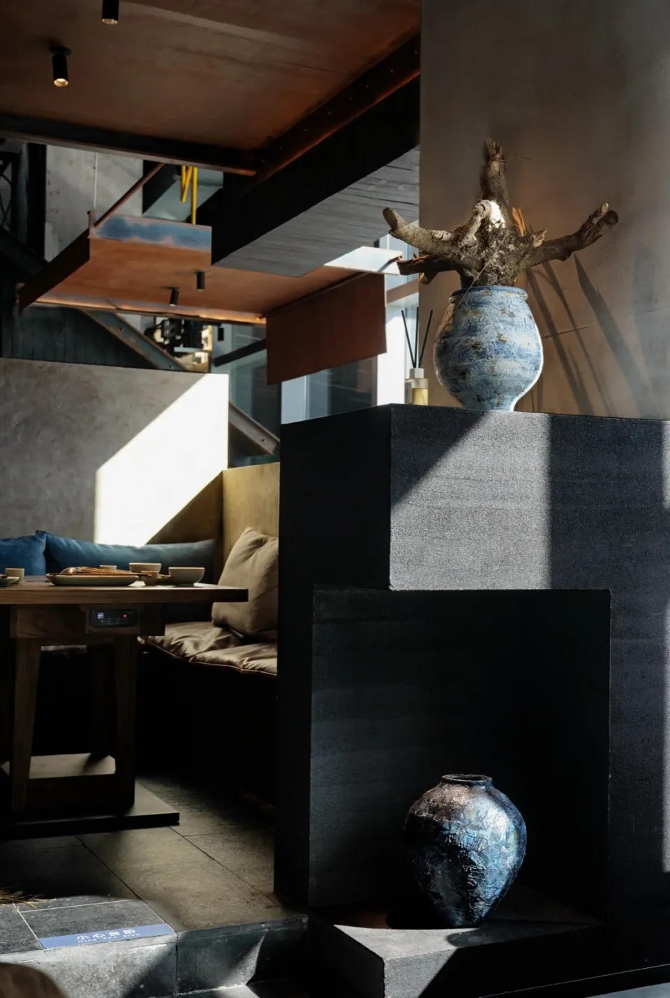 Industrial-style restaurant interior with concrete walls and a table adorned with plates and utensils.