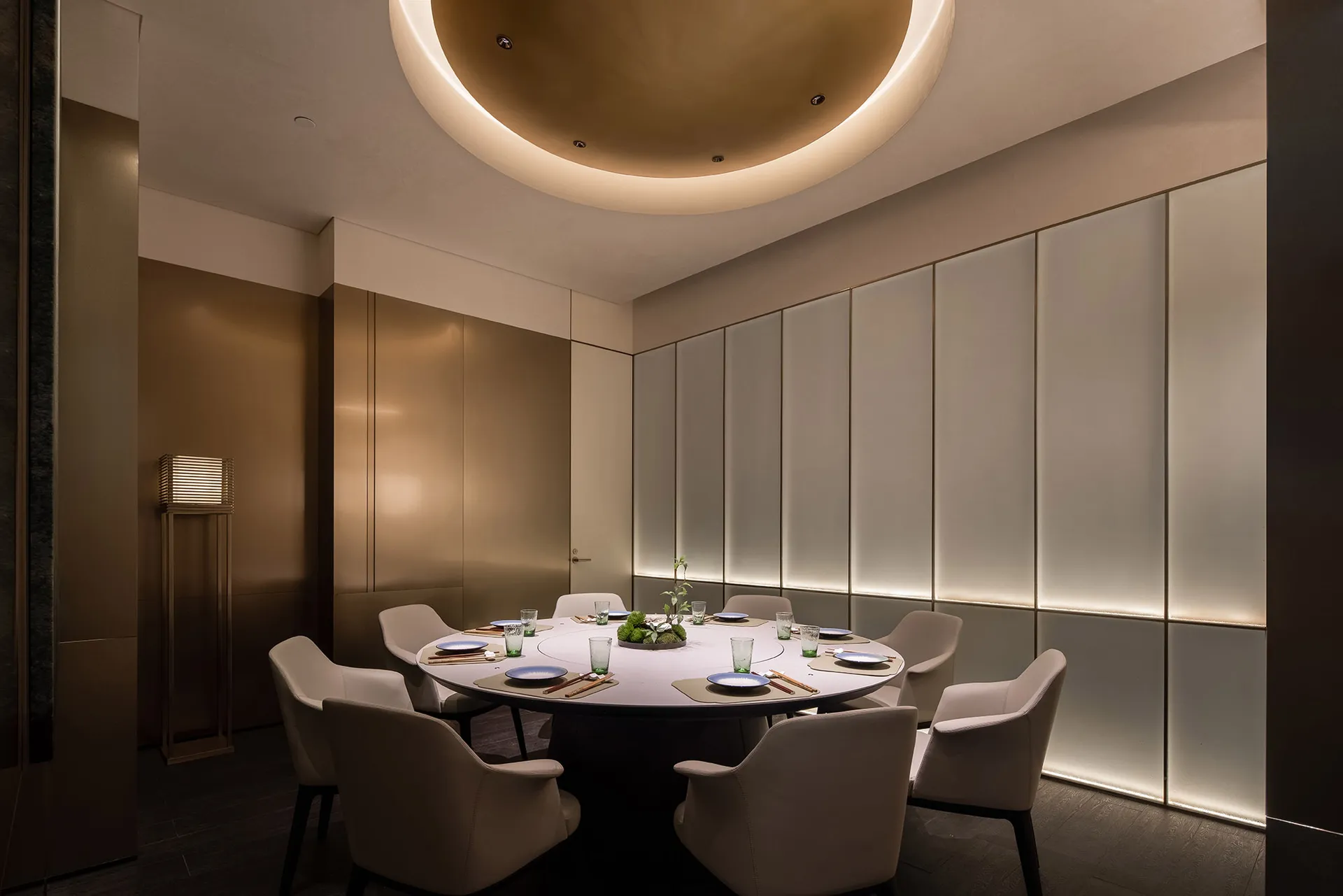 Modern elegant restaurant dining room with circular table, chairs, and decorative elements.