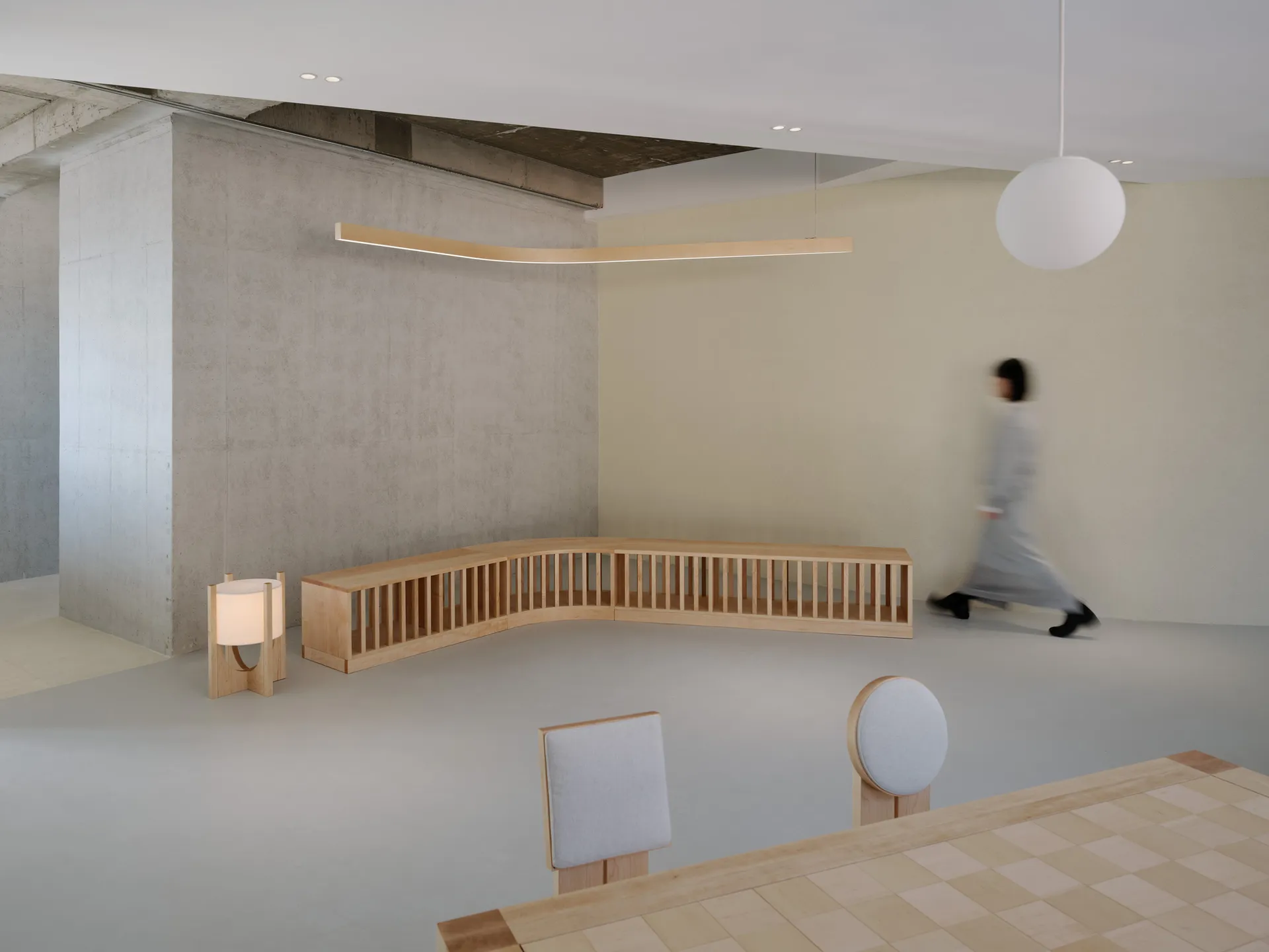 A modern waiting room featuring wooden seating and tables.