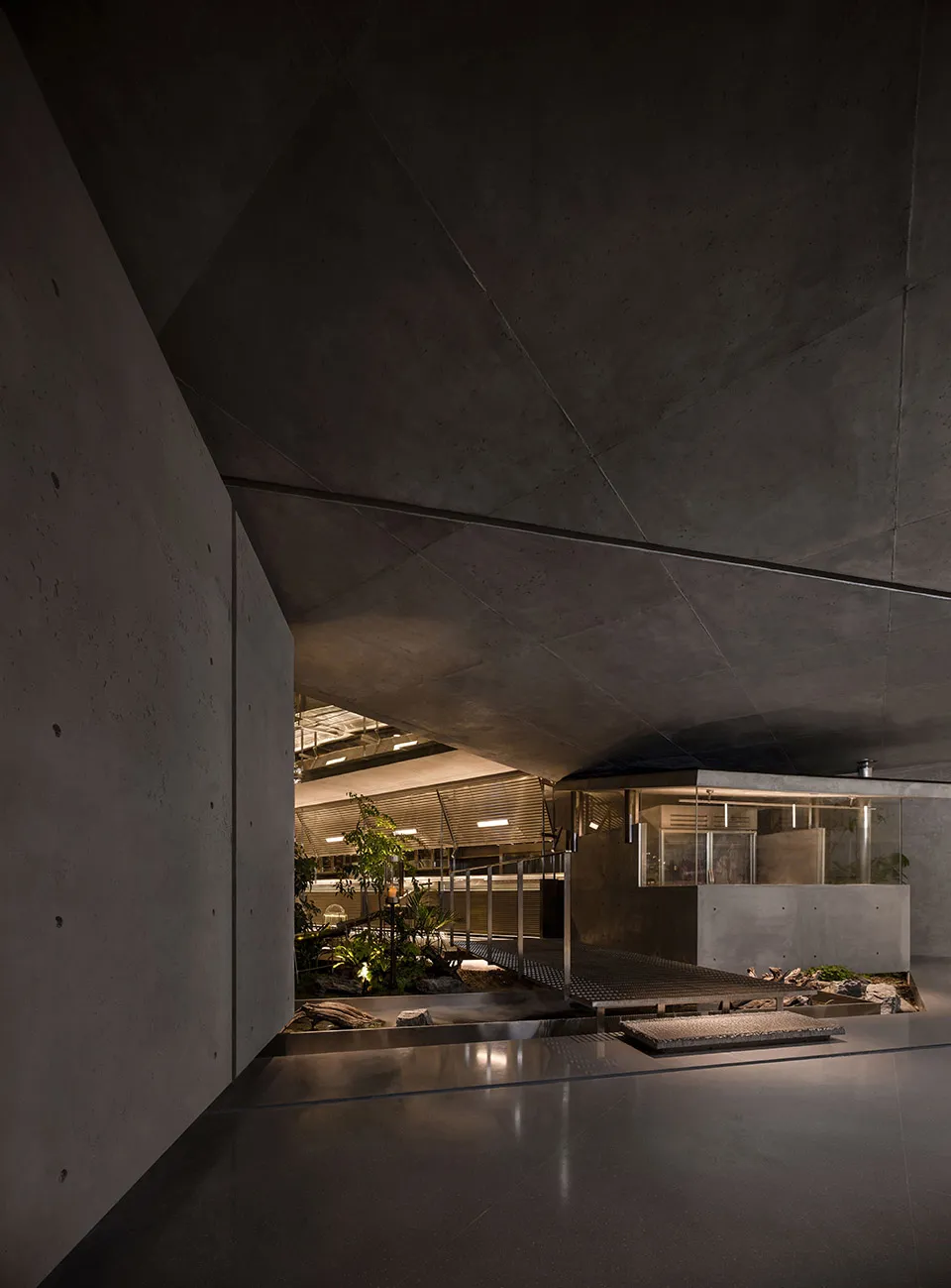 An industrial-style interior design featuring concrete walls and a courtyard with plants and stones.