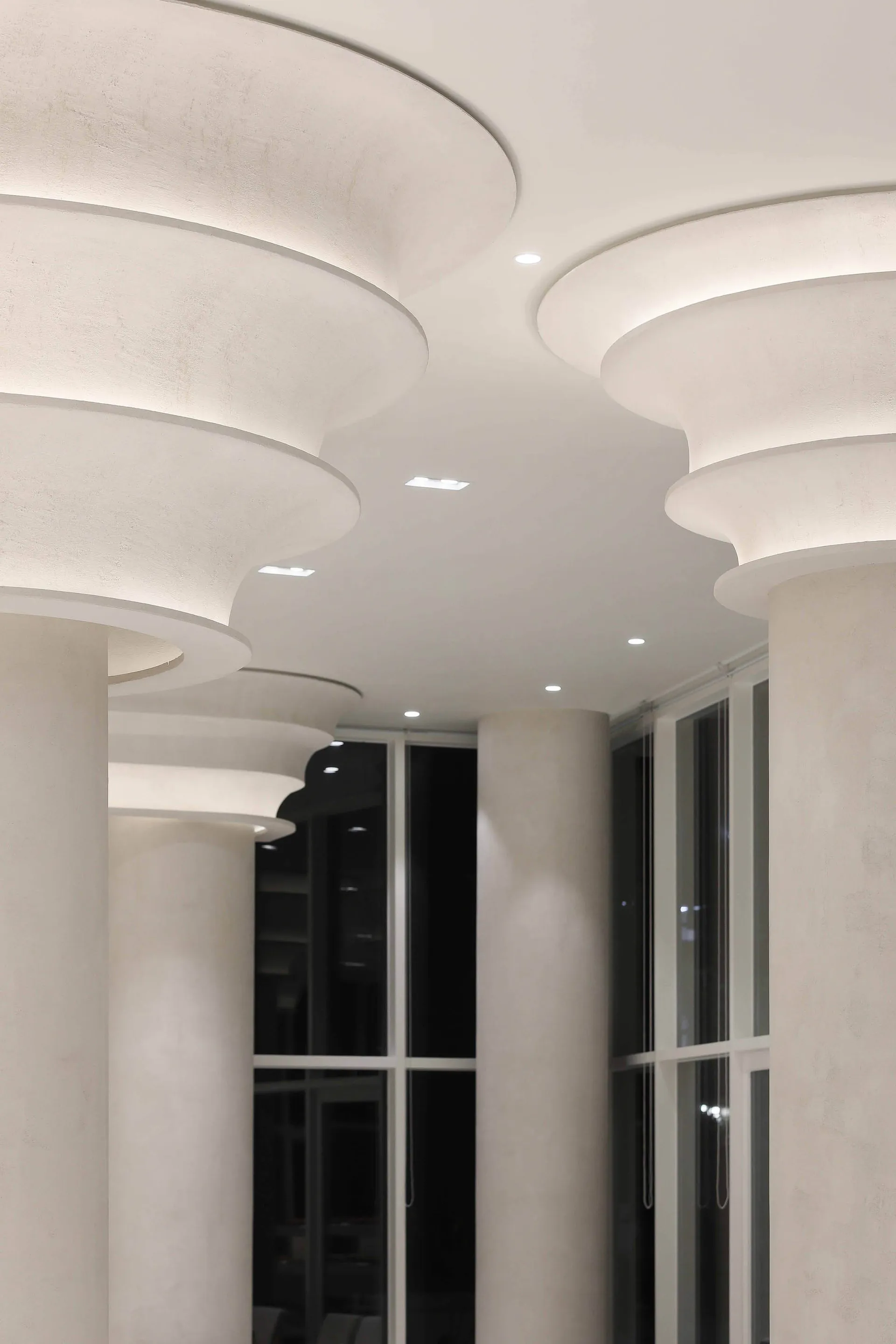 A corridor featuring decorative plaster columns illuminated by recessed lighting.