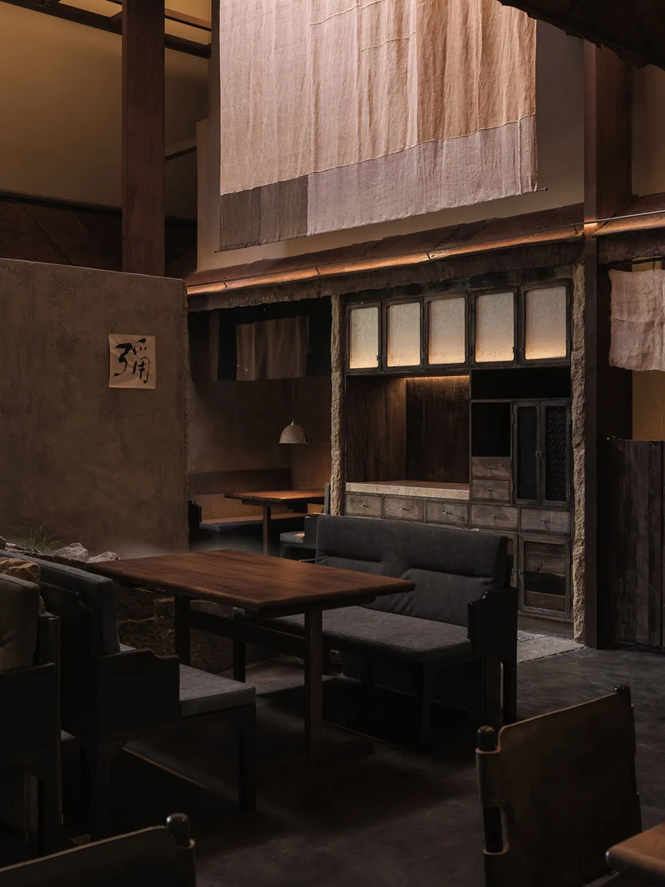 工業風主題的餐廳室內，搭配木質餐桌、石材牆面與布簾。