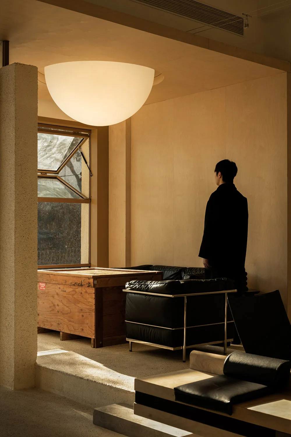 A minimalist home interior featuring a concrete floor, wooden walls, and leather furniture.