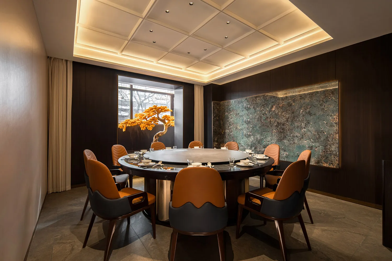 A modern interior design featuring contemporary furniture, a round dining table, and a decorative tree centerpiece.