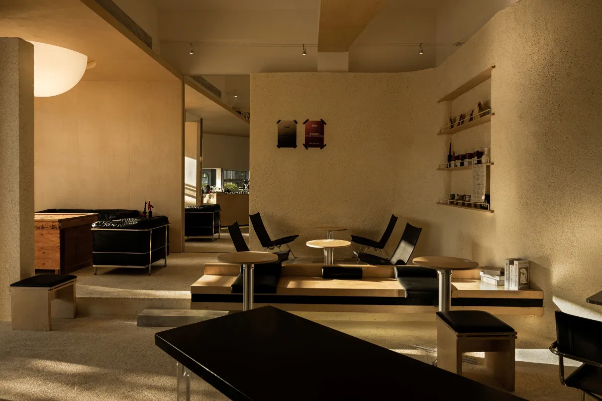 Modern restaurant interior with wooden and concrete seating, black leather accents, and minimalist design.