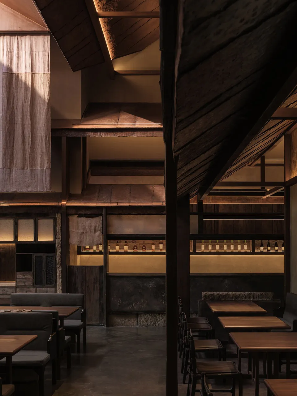 餐廳室內擺放木製餐桌,木架上陳列著瓶子。