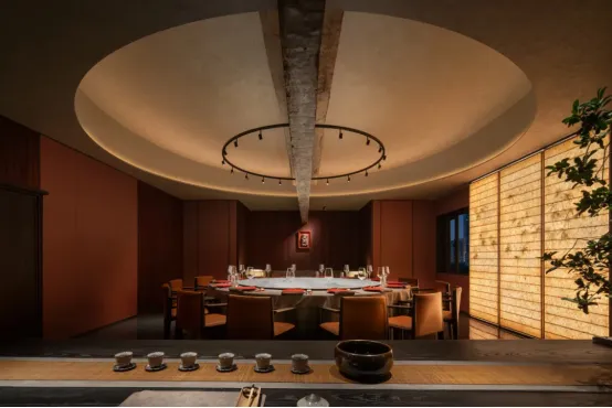 An elegant, modern restaurant interior with wooden elements and a circular ceiling light fixture.
