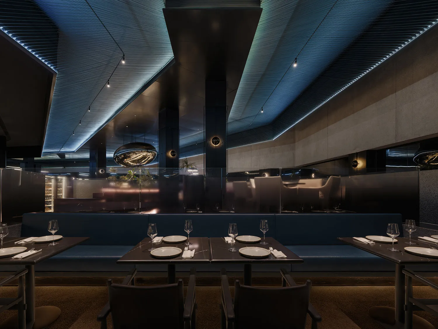 Modern, industrial restaurant interior with exposed metal ceiling, concrete walls, and glass partitions.