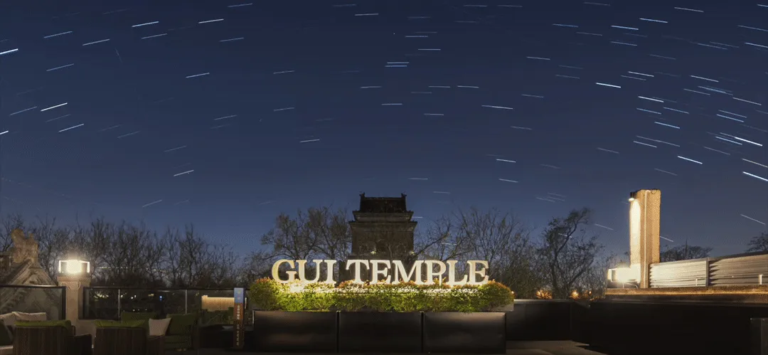 夜空繁星與前景寺廟招牌,由戶外燈光照亮。