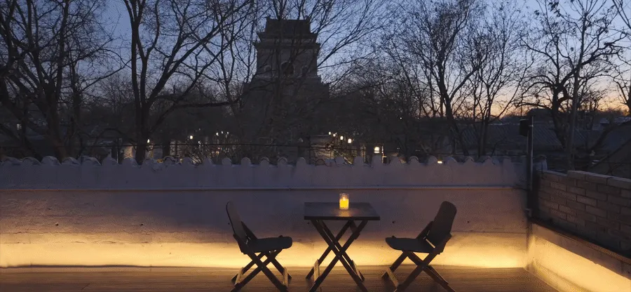 A minimalist wooden terrace with a candle on a small table.