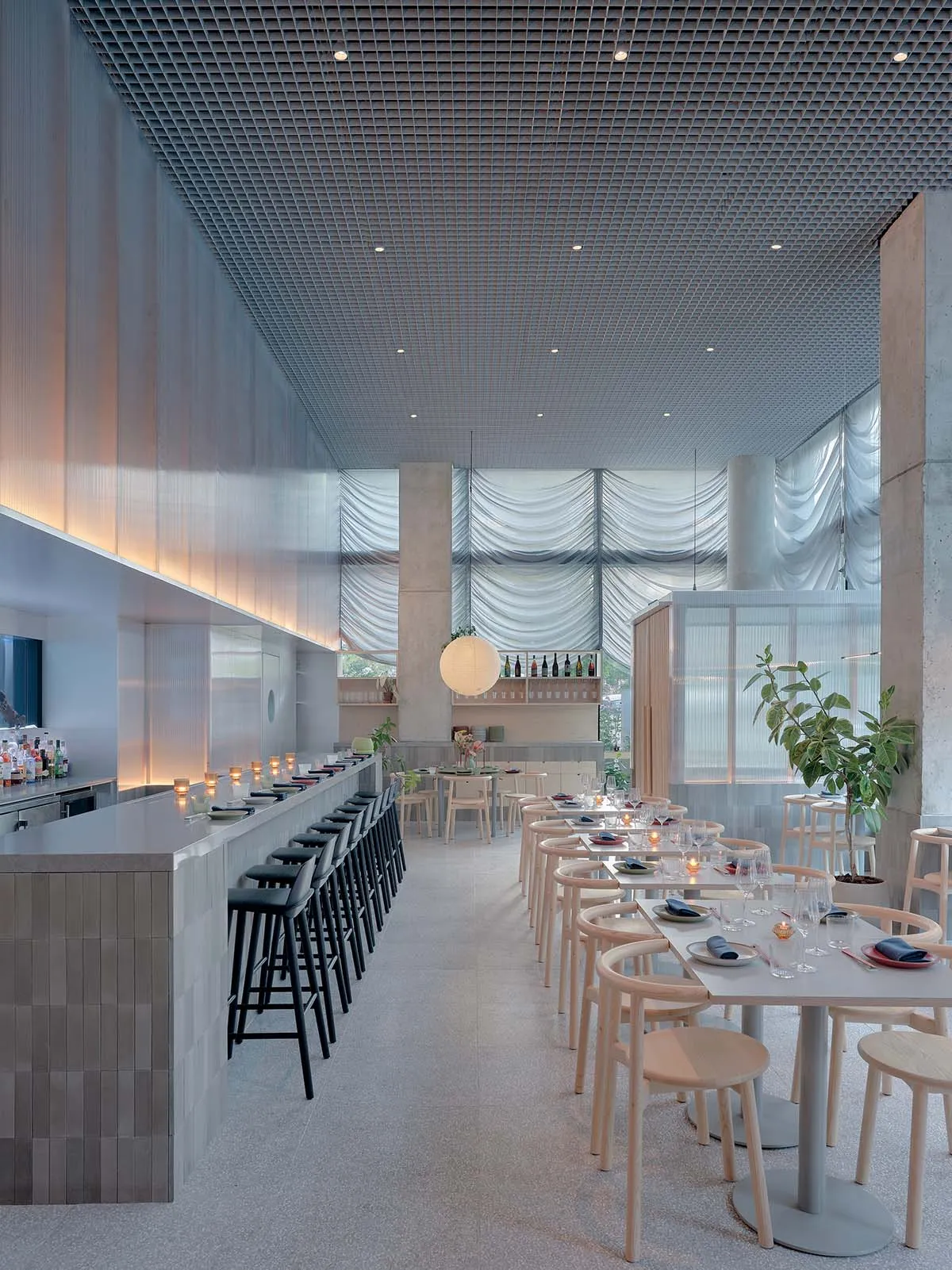 A modern restaurant interior featuring exposed concrete walls and wooden accents.