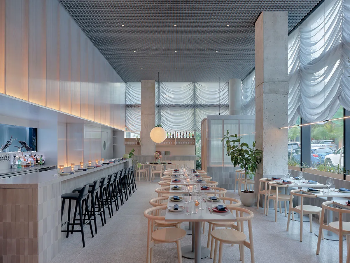 Modern restaurant interior with concrete walls, glass partitions, and minimalist design.