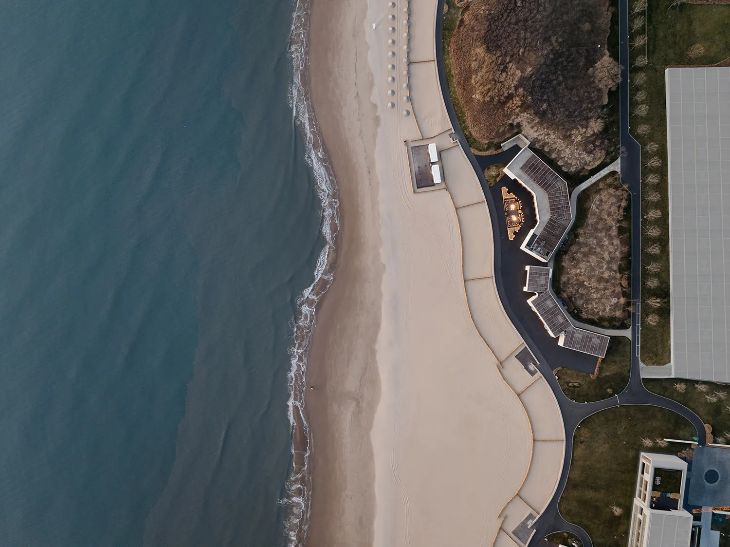 An aerial view of a beachfront architecture with sandy beach and ocean waves.