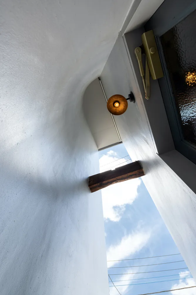 A minimalist interior space featuring a window with a wooden frame and a warm light bulb.