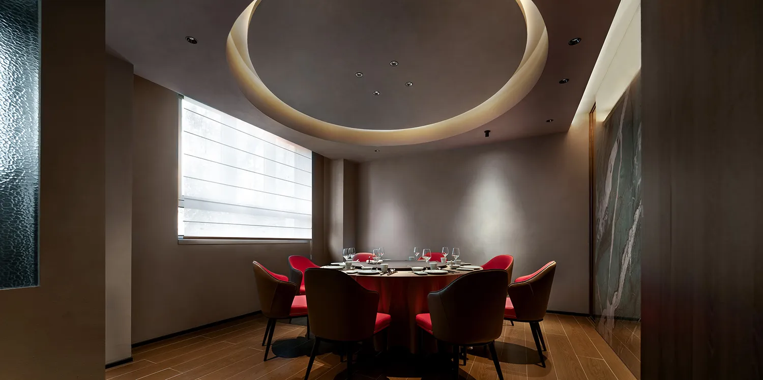 Modern dining room with concrete walls, red accent walls, and a round dining table.