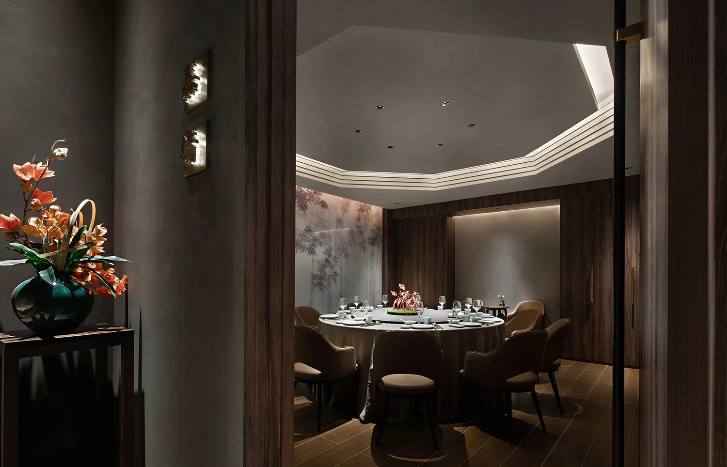 A modern restaurant dining room with dark wood accents and a round table set for a meal.