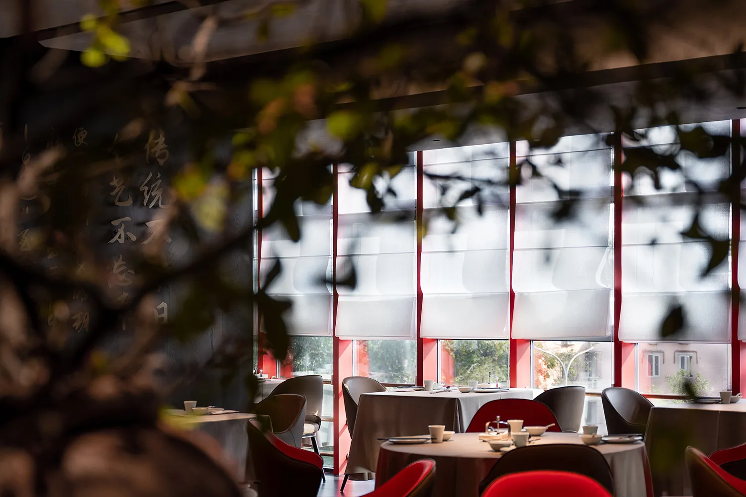 Modern restaurant interior with white blinds and white tablecloths.