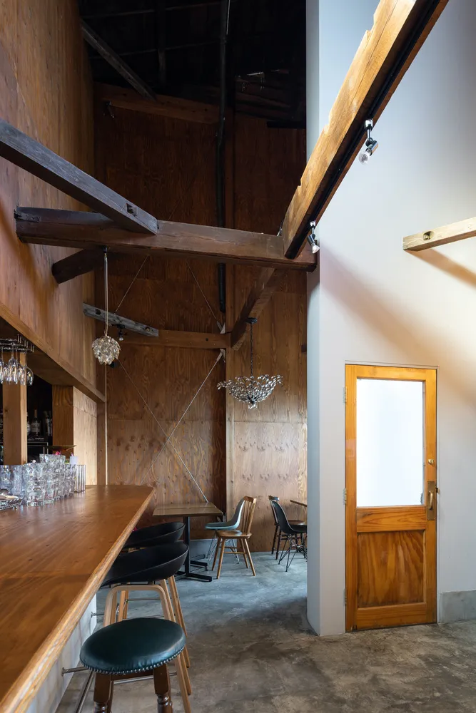 A modern restaurant bar interior with concrete flooring and wooden beams